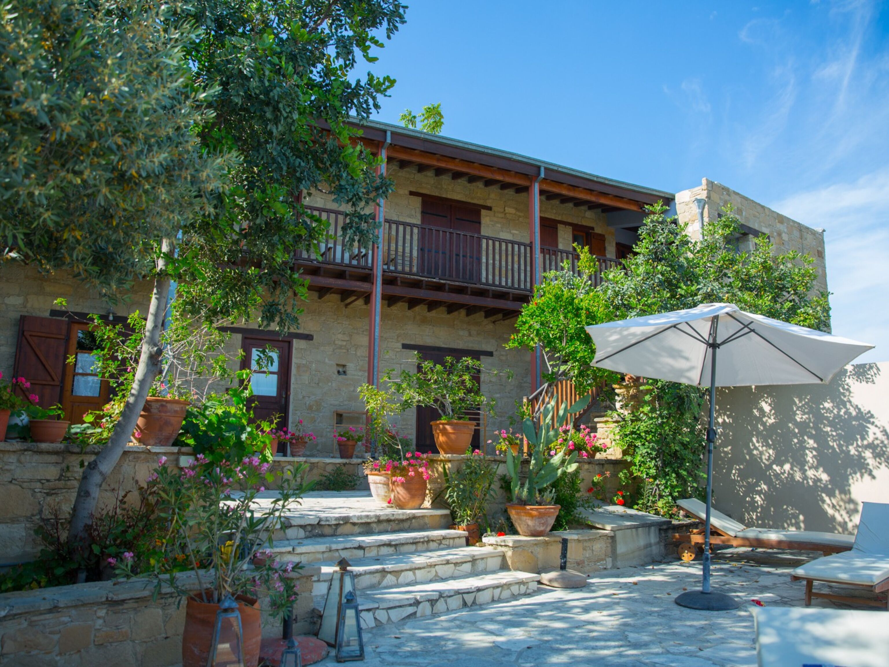 A stone building with a balcony, potted plants, and outdoor seating.