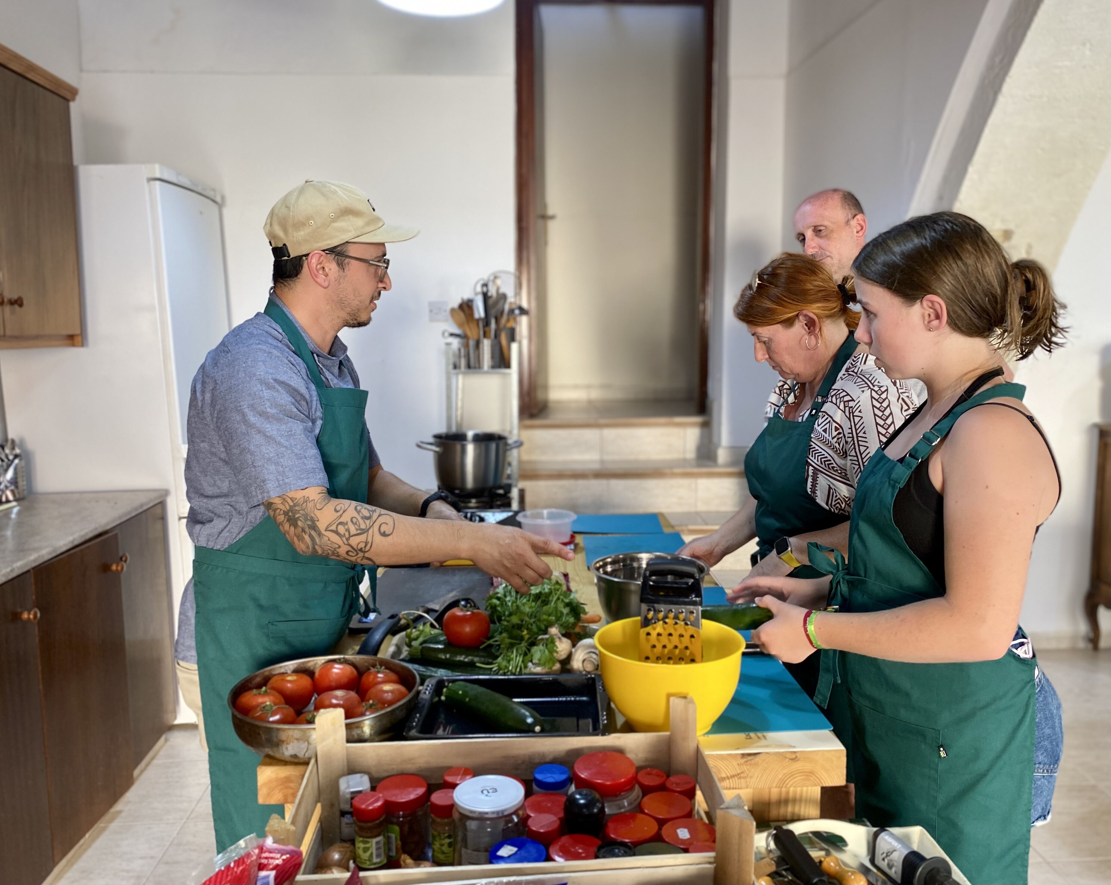 A kitchen with a wooden countertop, a stove, and various cooking utensils. There are several people preparing food.