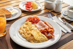 Un plato de desayuno con huevos, tocino y tomates.