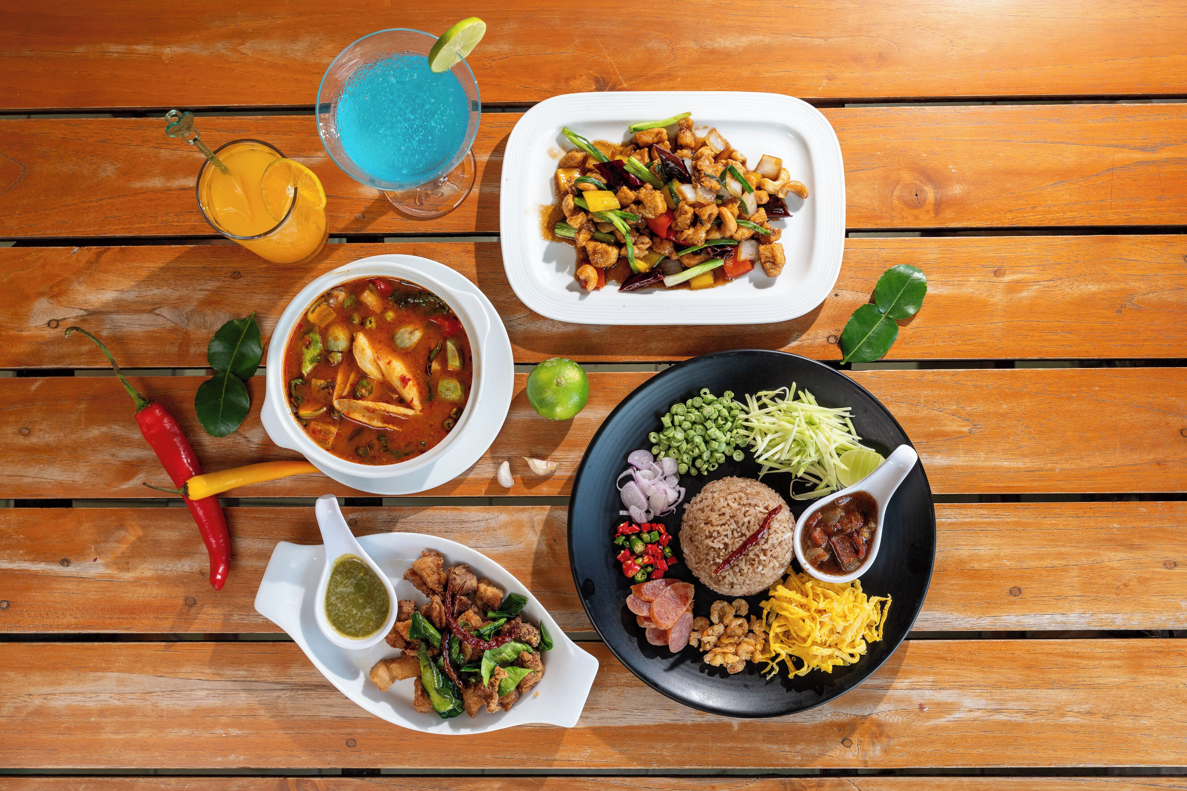 Una mesa de madera con varios platos, incluyendo un tazón de sopa, un plato de vegetales salteados y una porción de arroz con acompañamientos.