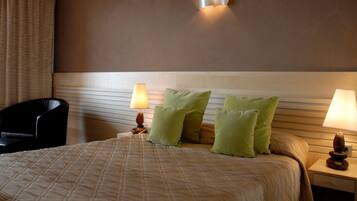 A hotel room with a bed, two bedside lamps, a chair, and a wall-mounted light fixture.