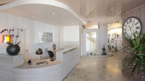 Un área de recepción con un mostrador curvo, un reloj de pared grande y una planta en maceta.