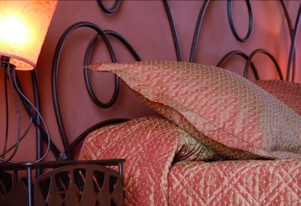 A bed with a patterned blanket and pillows, a metal headboard, and a lamp. - Hotel Capo Rosso (Piana)