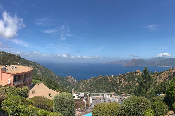 A coastal hotel with a pool, outdoor seating, and a view of the sea. - Hotel Capo Rosso (Piana)