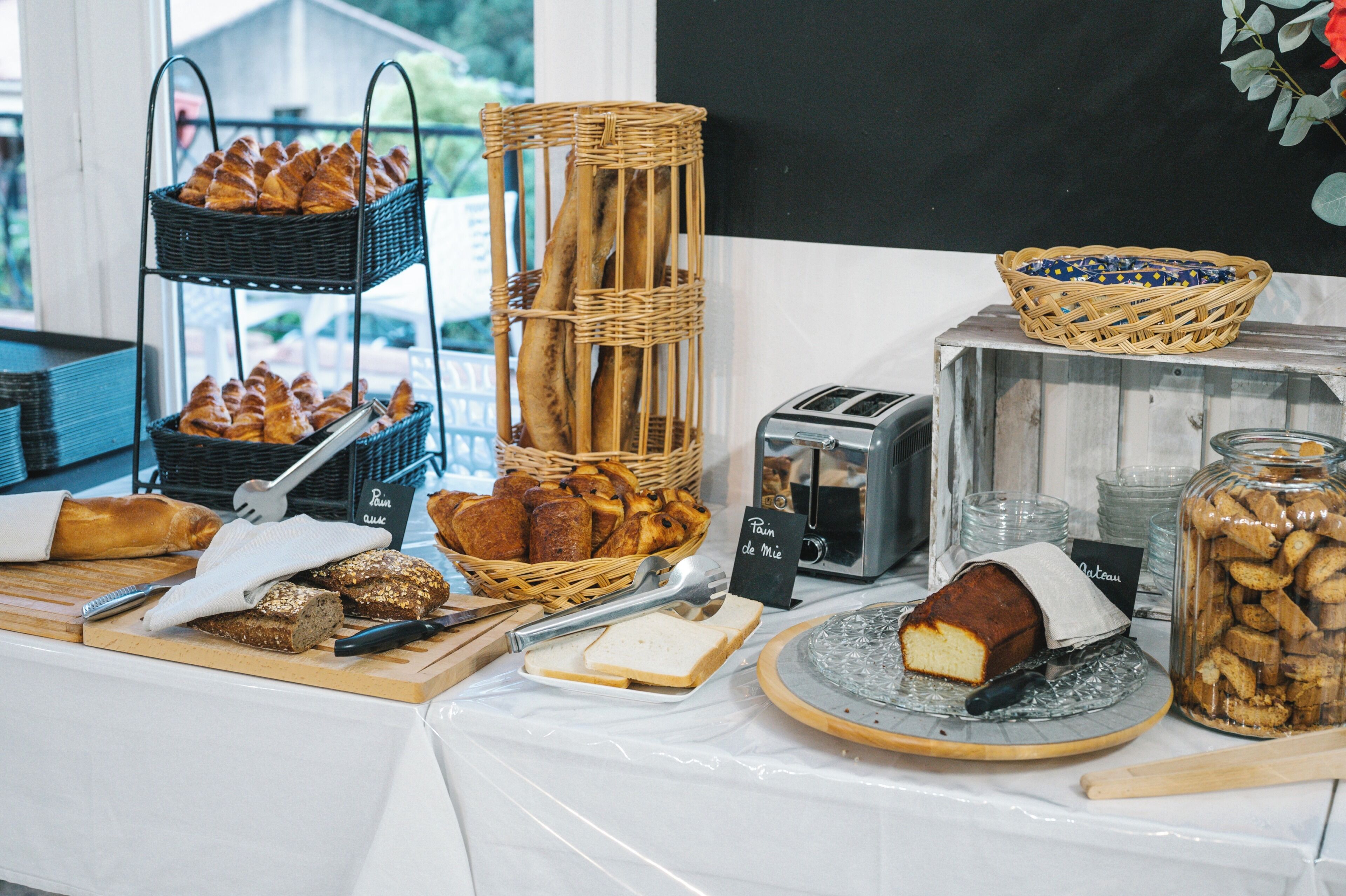 A breakfast buffet with various breads, pastries, and a toaster.
