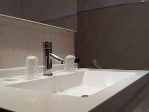 A modern bathroom with a white sink, chrome faucet, and clear glass soap dispensers. - Hotel le Vaita (Ota)