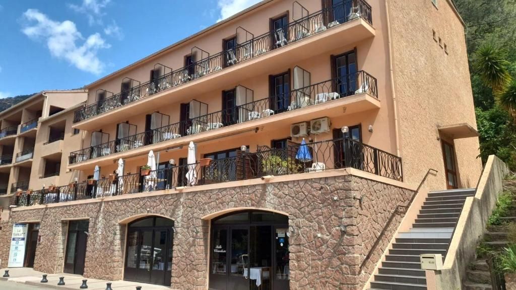 Un hôtel à plusieurs étages doté de balcons, de sièges en plein air et d’une façade en pierre.