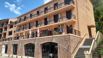 Un hôtel à plusieurs étages doté de balcons, de sièges en plein air et d’une façade en pierre.