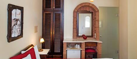 Habitación de hotel con cama, escritorio, kitchenette pequeña y baño con espejo y ducha.