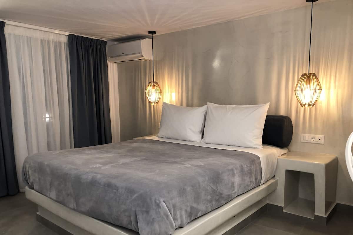 Een moderne slaapkamer met een groot bed, nachtkastjes en een wandgemonteerde airconditioner.