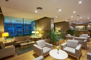 Un lobby moderno con sofás, mesas y una zona de bar.