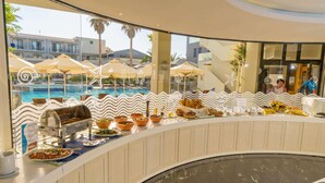 A buffet area with a pool view, featuring a variety of food items and a barbecue station. - Pearl Beach Hotel (Rethymno)