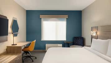 Une chambre d’hôtel avec un lit, un bureau, une chaise et une grande fenêtre.