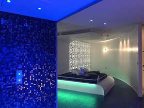 Une chambre moderne avec un lit, un mur orné d’un motif en mosaïque et un mur décoré d’un motif se trouvant derrière le lit.