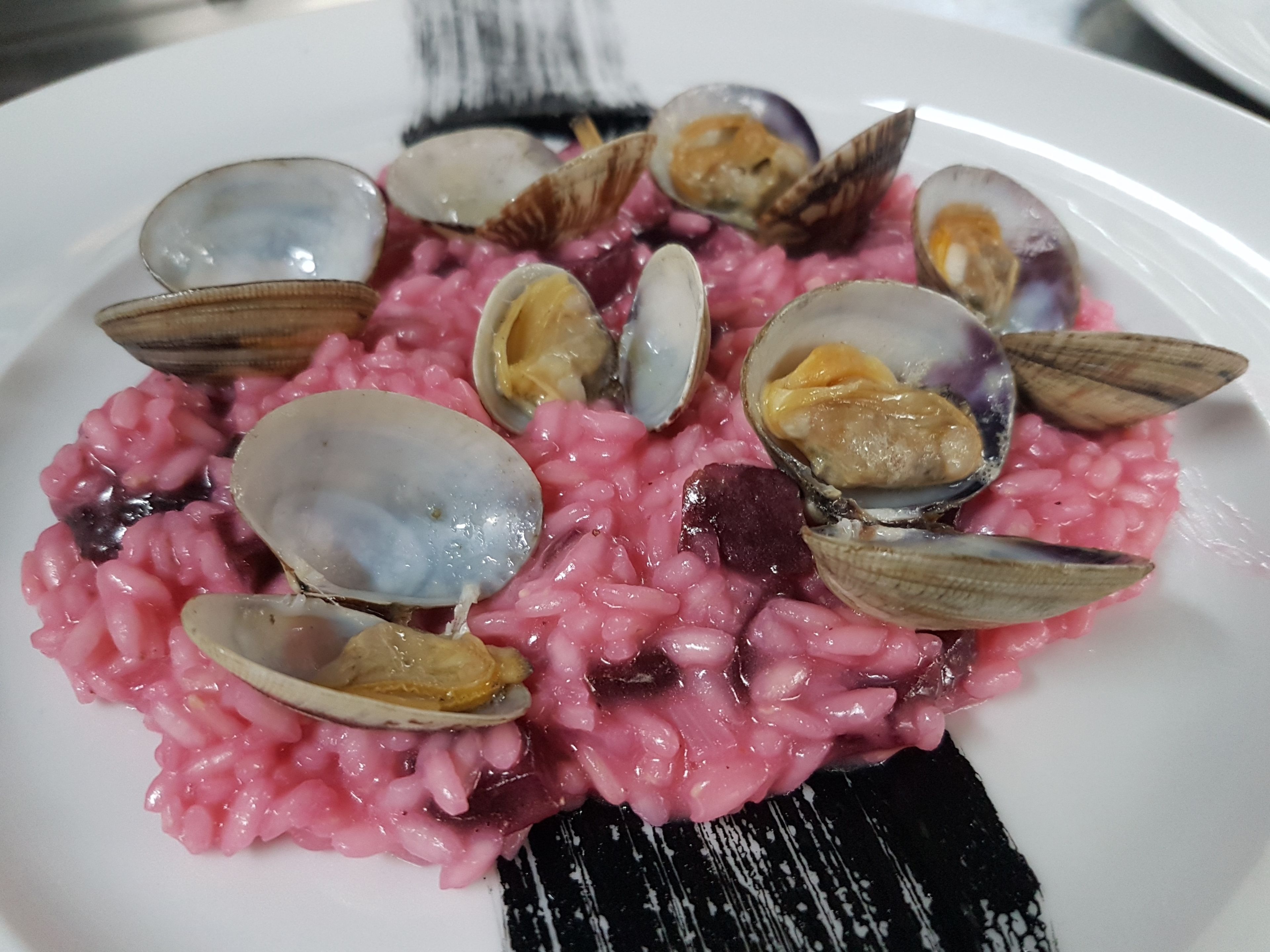 Une assiette de risotto rose aux palourdes.
