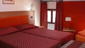 A hotel room with a large bed, a nightstand, a lamp, and a window with curtains.