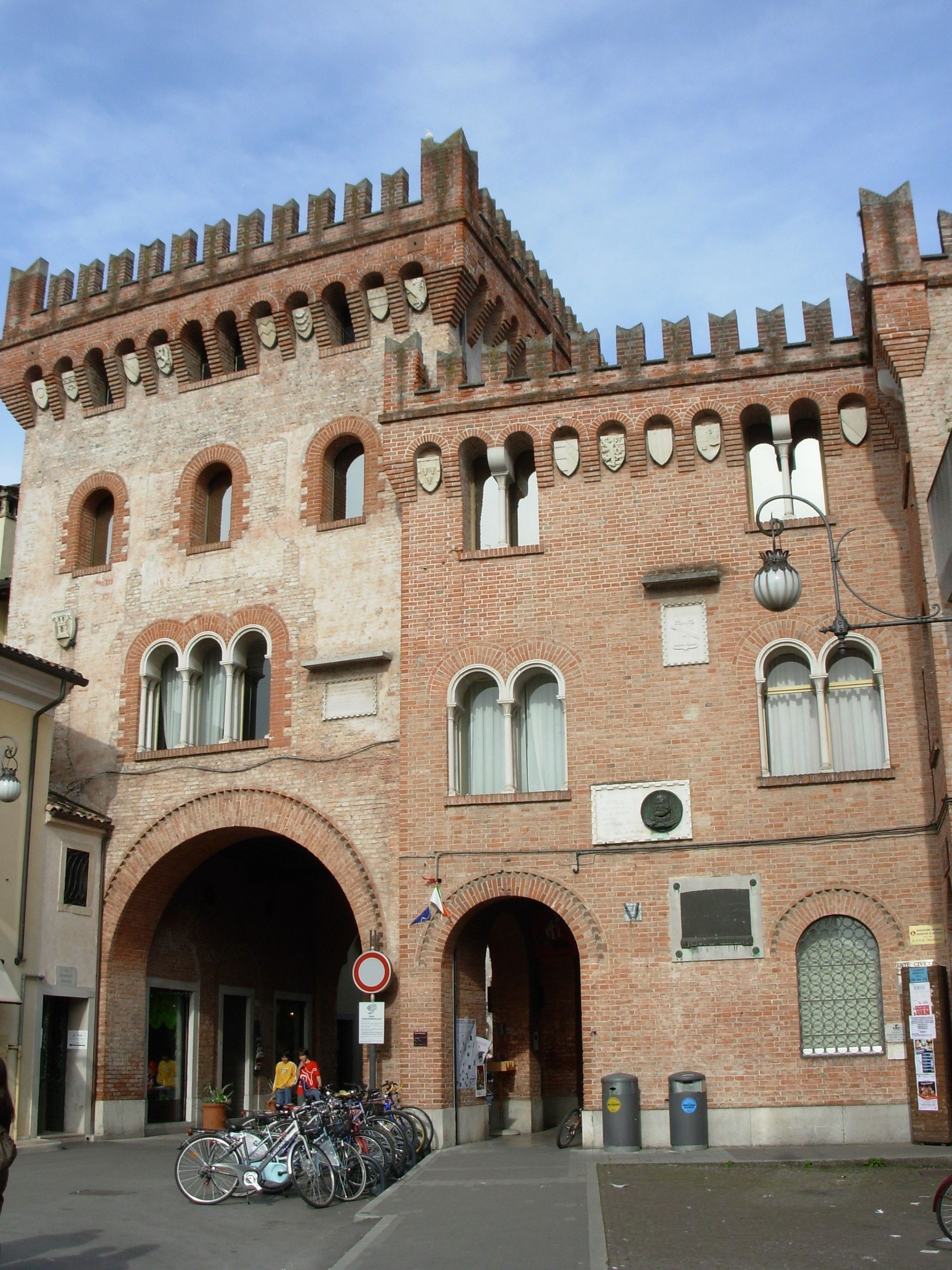Um edifício histórico com uma grande entrada em arco, várias janelas e uma série de arcos menores no nível superior.