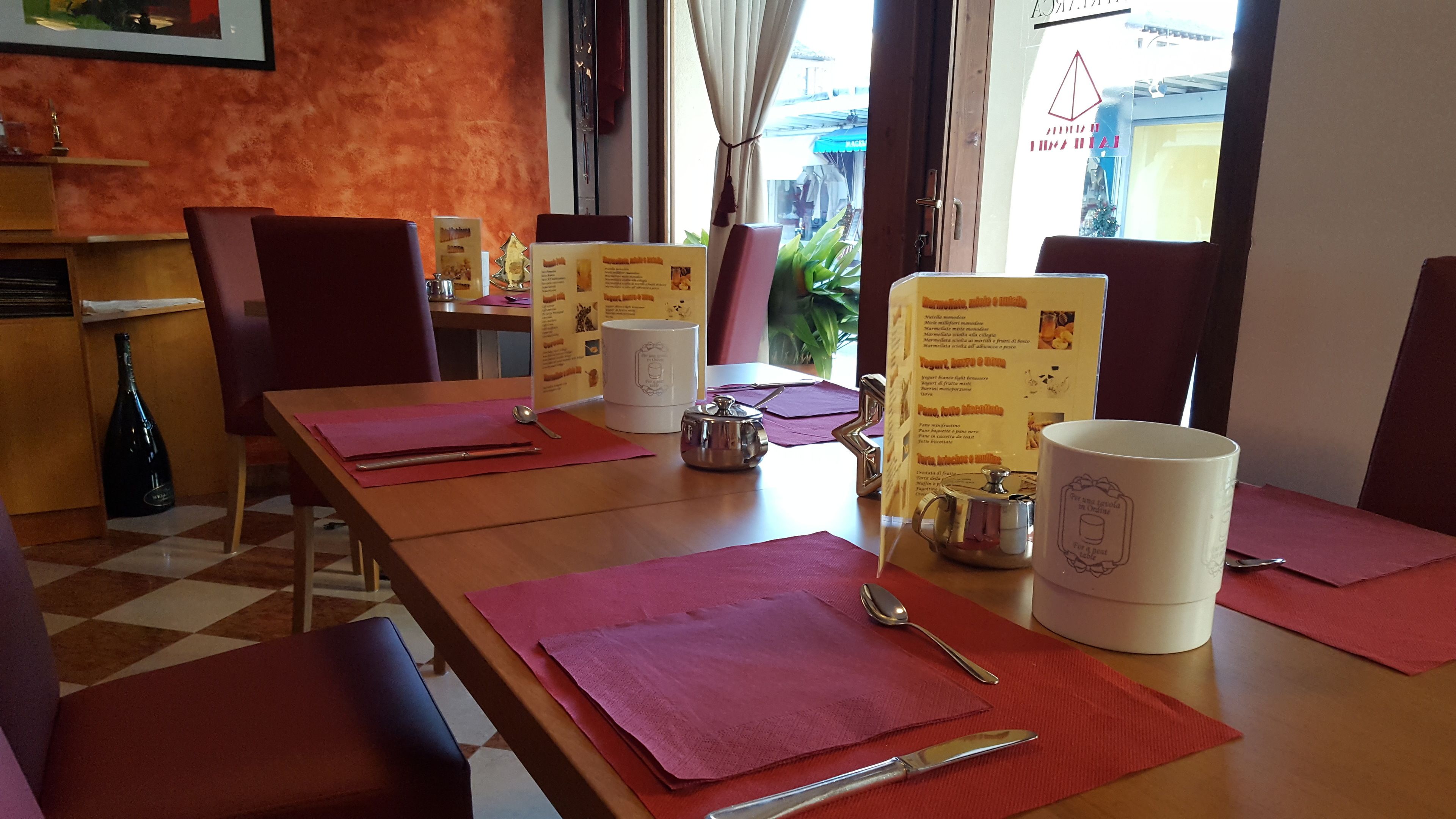 Interior de restaurante con mesas de madera, individuales rojos y menús.