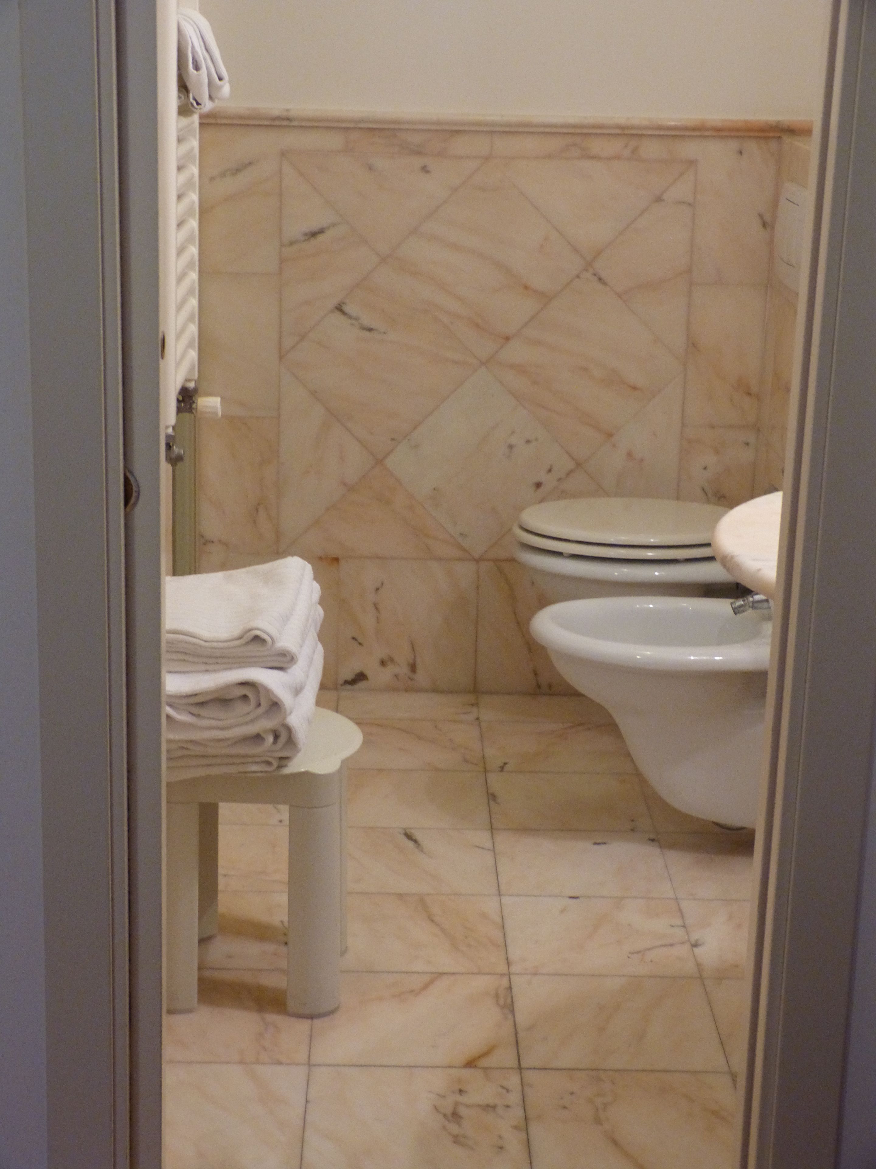 Un baño con inodoro, lavamanos y toallero.