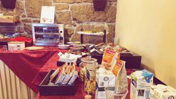 A buffet table with various food items, including pastries, bread, and condiments.