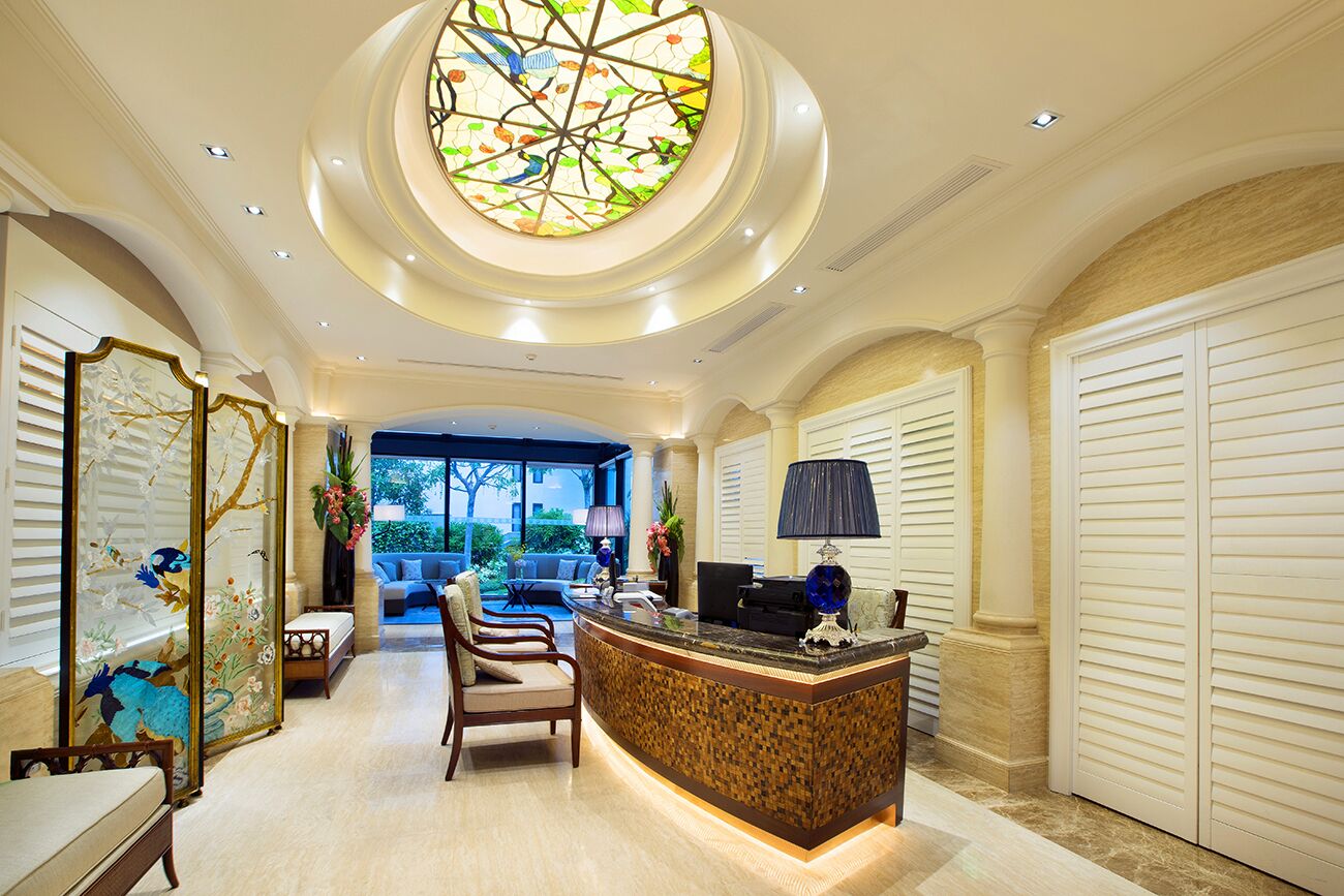 A hotel lobby with a reception desk, seating area, and a large stained glass window.