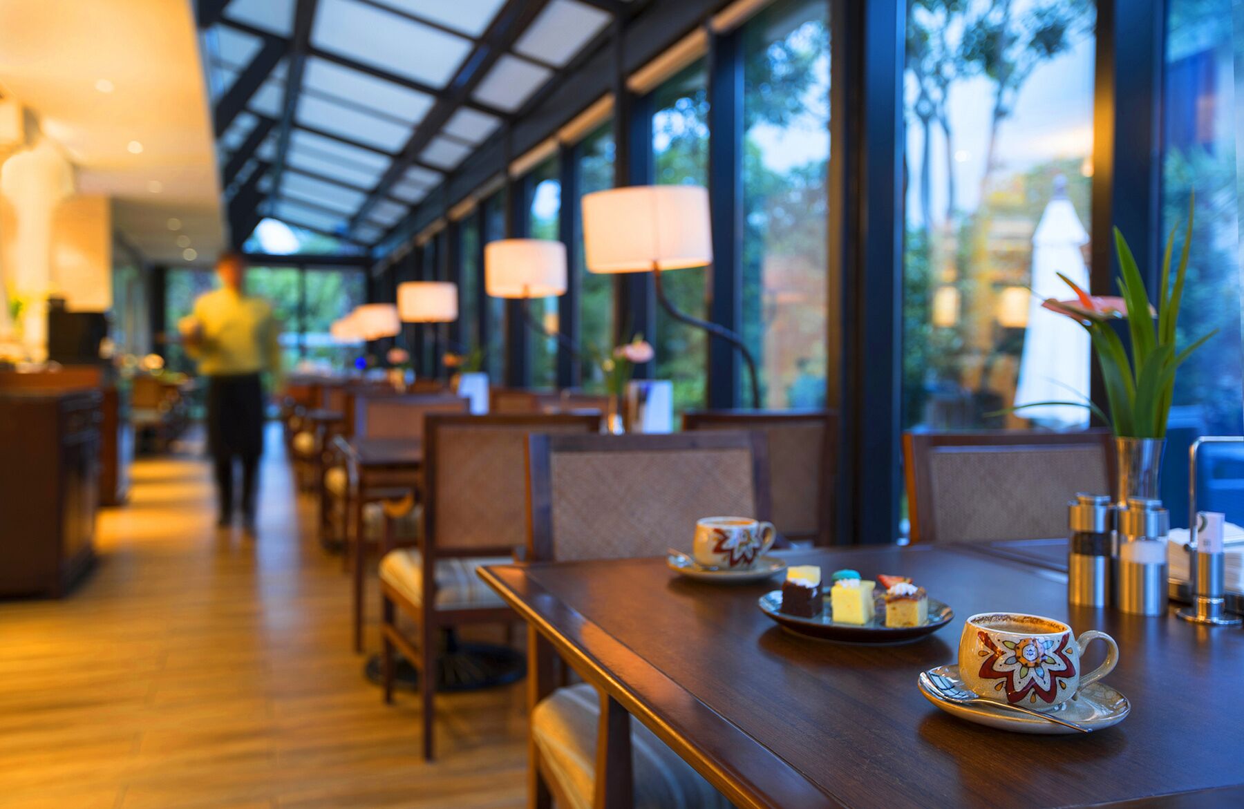 A restaurant interior with tables, chairs, and a person walking in the background.