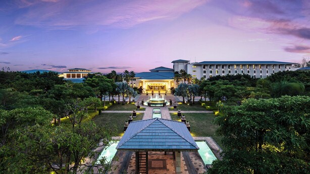 Un hotel con un patio central, una fuente y una zona de piscina.