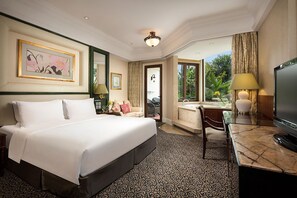 A hotel room with a large bed, a desk with a television, a chair, a desk lamp, a window with curtains, and a painting on the wall. - Seaview Resort Xiamen (Xiamen)