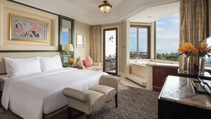 Habitación de hotel con una cama grande, una zona de estar, un escritorio, un baño y vistas al exterior.