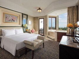Habitación de hotel con una cama grande, una zona de estar, un escritorio, un baño y vistas al exterior.