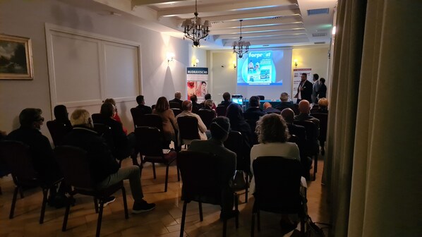A conference room with attendees facing a presentation screen. - Saturnia Tuscany Hotel (Manciano)