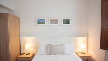 A hotel room with a large bed, two bedside tables with lamps, and three framed pictures on the wall.