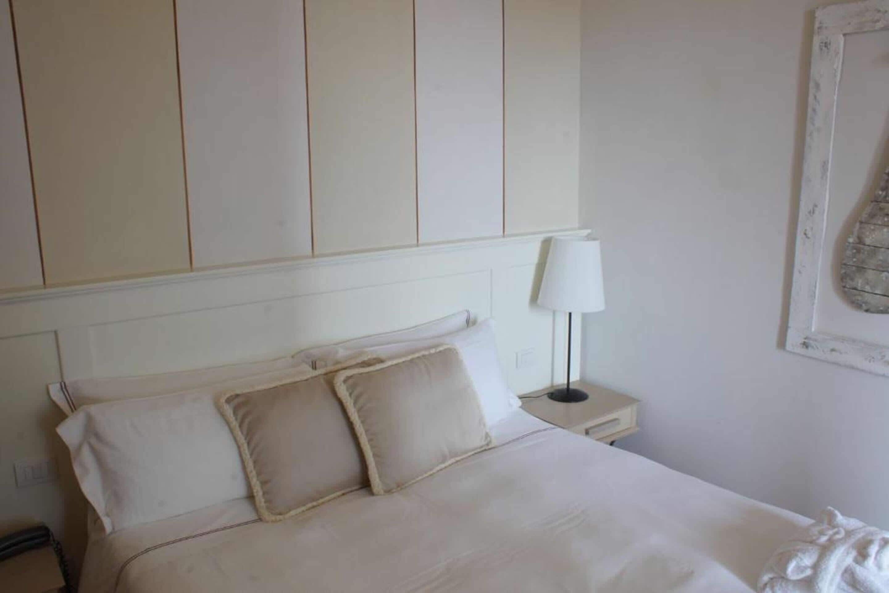 A hotel room with a bed, a nightstand, a lamp, and a framed picture on the wall.