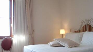 A hotel room with a bed, a chair, a lamp, and a window with curtains.