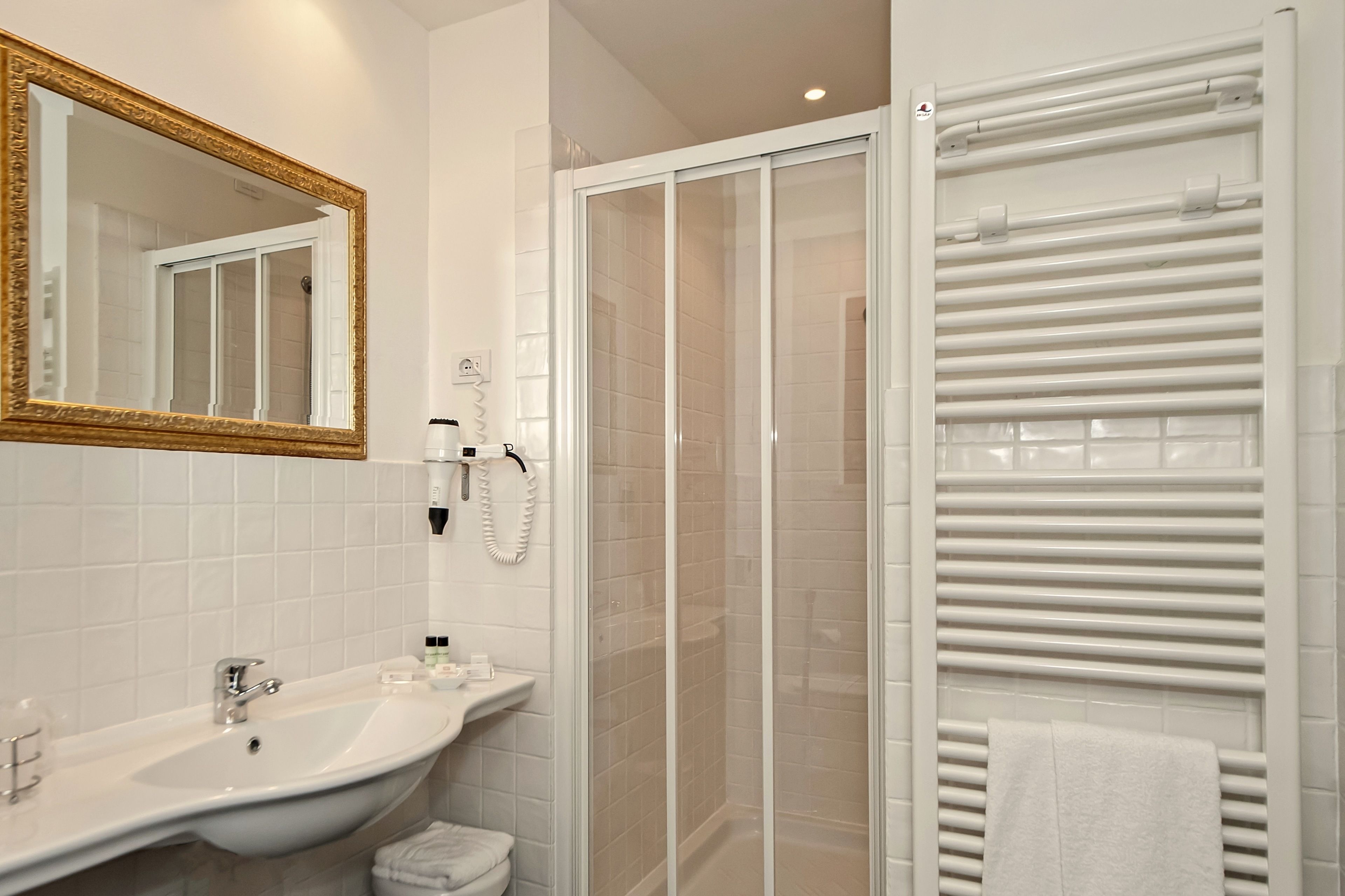 A bathroom with a sink, mirror, towel rack, and a glass shower enclosure.