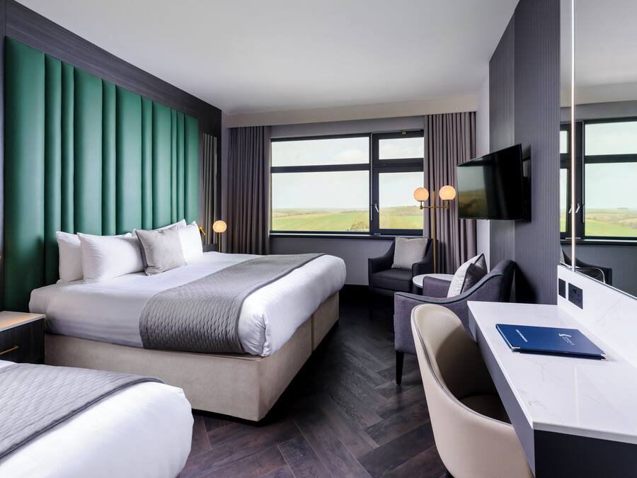 Une chambre d’hôtel avec un grand lit, un bureau, une chaise, une télévision et une vue sur la campagne.