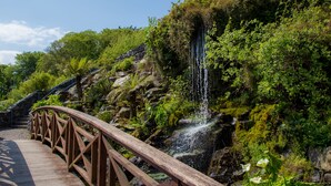 A wooden bridge leading to a waterfall surrounded by lush greenery. - Kinsale Hotel & Spa (Kinsale)