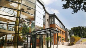 A modern building with large glass windows, a covered entrance, and potted plants. - Kinsale Hotel & Spa (Kinsale)