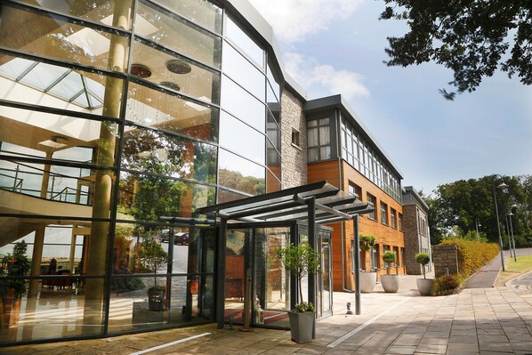 A modern building with large glass windows, a covered entrance, and potted plants. - Kinsale Hotel & Spa (Kinsale)