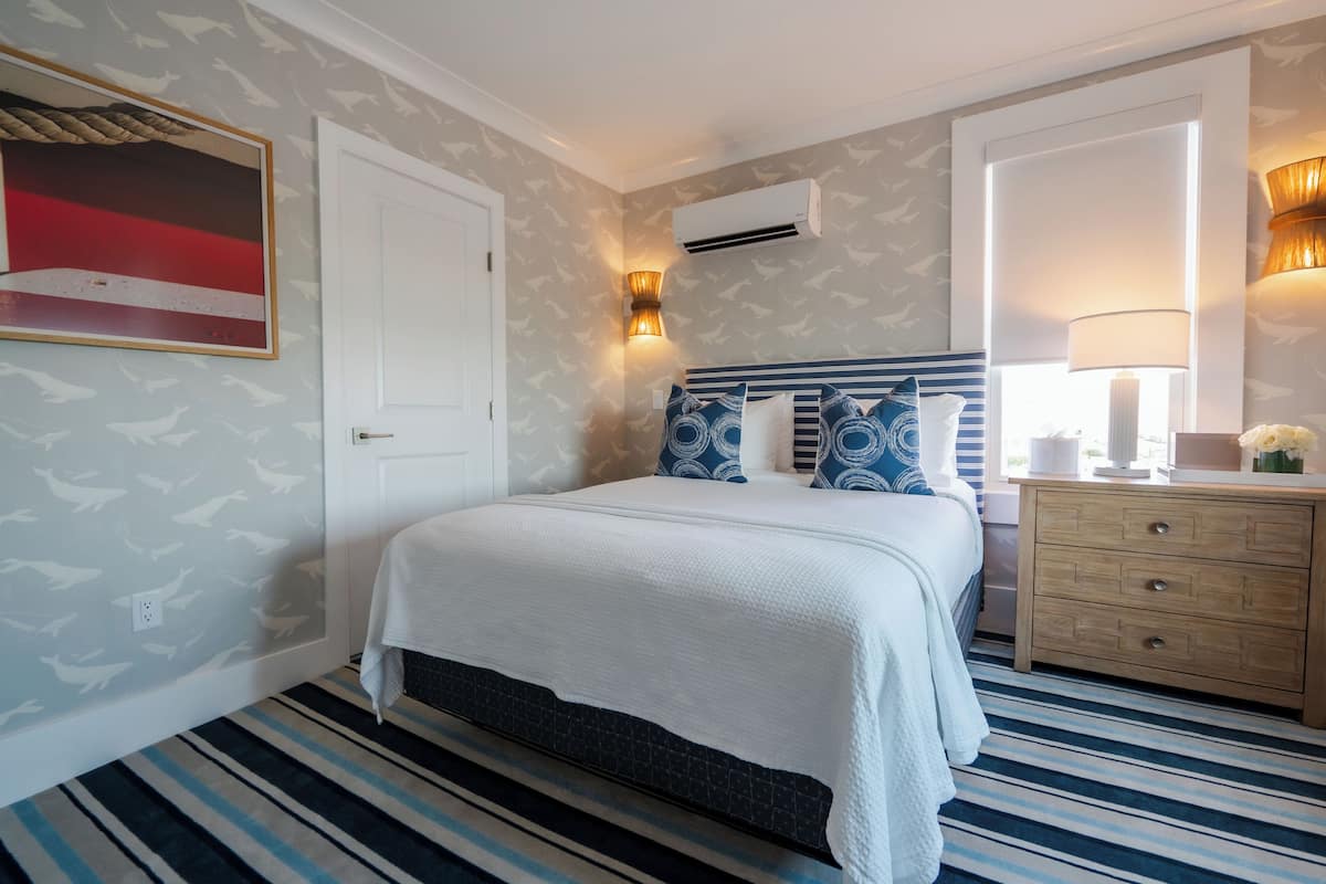 Ein Schlafzimmer mit Bett, Kommode, Wandklimaanlage und einem Gemälde.