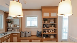 Una cocina con armarios de madera, un ventanal y luces colgantes.