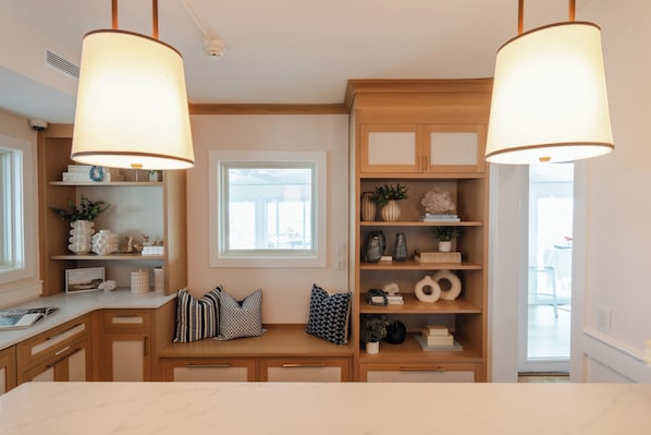 A kitchen with wooden cabinets, a window, and pendant lights.