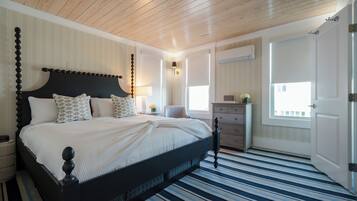 Un dormitorio con cama, mesitas de noche, cómoda, ventana y puerta.