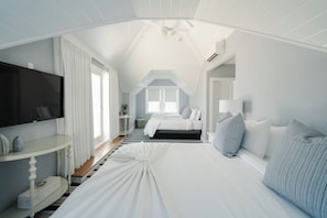 A bedroom with a bed, a TV, a bedside table, and a window. - Grand Victorian - Spring Lake (Spring Lake)