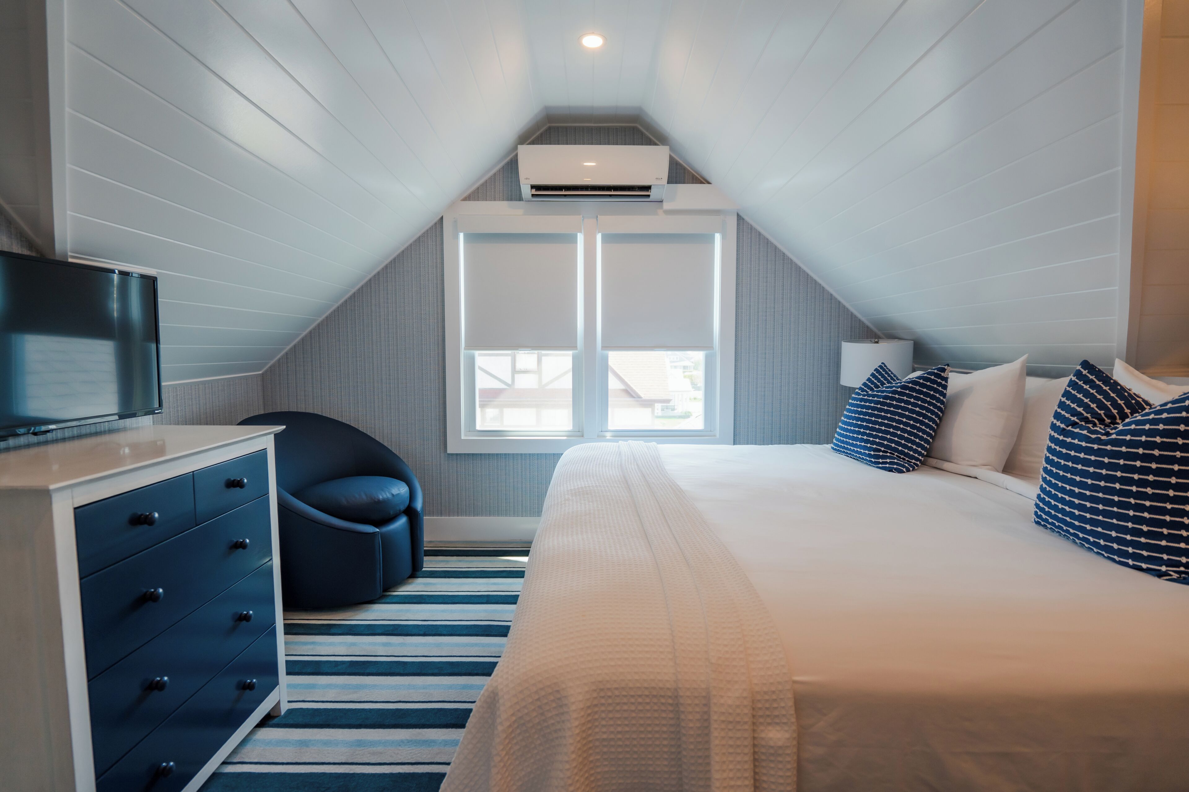 A bedroom with a bed, a dresser, a chair, and a window.