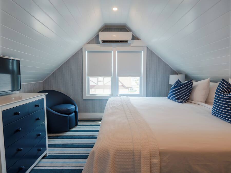 A bedroom with a bed, a dresser, a chair, and a window.