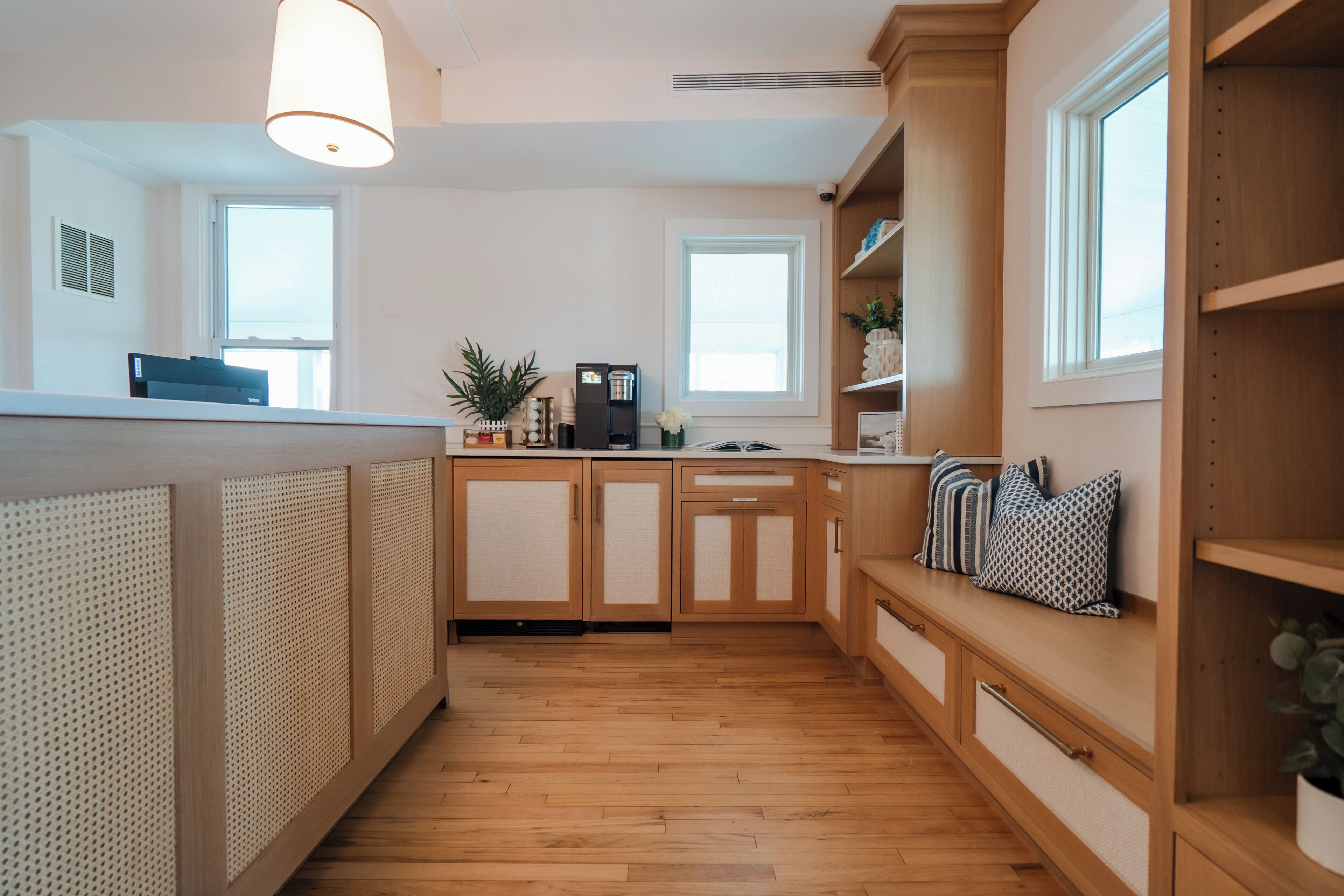 A modern kitchen with wooden cabinets, a built-in bench with cushions, and a coffee machine.