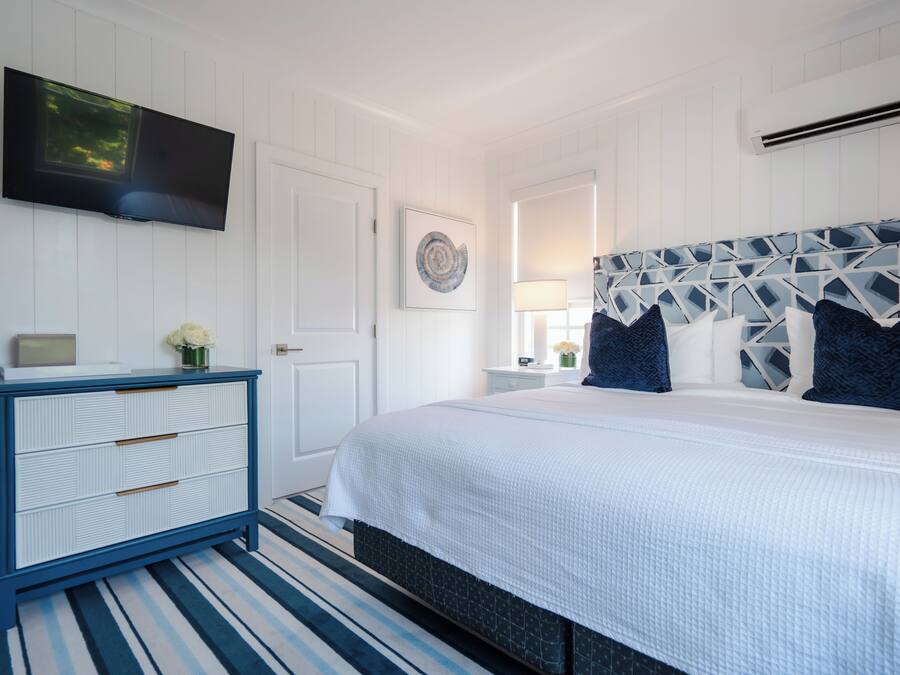 A bedroom with a bed, a dresser, a TV, and a wall-mounted artwork.