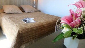 A hotel room with a bed, a bedside table, a lamp, and a floral arrangement. - Bliss Hôtel (Cogolin)