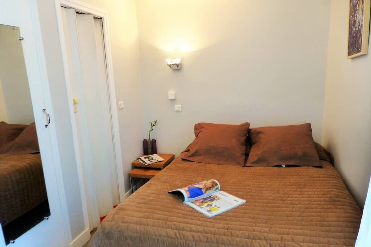 Ein Schlafzimmer mit Bett, Nachttisch, Zeitschrift und Wandlampe.
